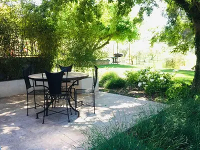 a table and chairs on a patio under a tree at Gîte ,studio dans le village de lagnes in Lagnes