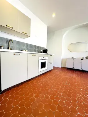 a kitchen with white cabinets and a red floor at Design and Provençal Elegance Suite in Aix in Aix-en-Provence