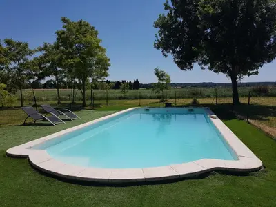 a large swimming pool in the grass with two chairs at Évasion provençale in Saint-Cannat