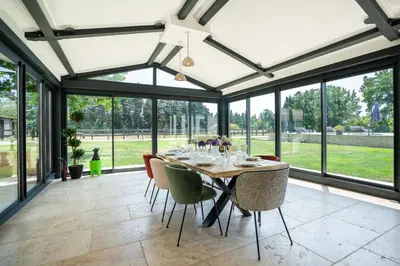 a dining room with a table and chairs and windows at Mas Provençal chic et élégant - Alpilles et Luberon in Sénas