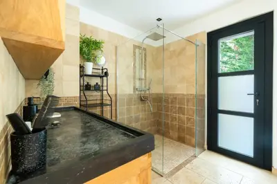 a bathroom with a shower with a black counter top at Mas Provençal chic et élégant - Alpilles et Luberon in Sénas