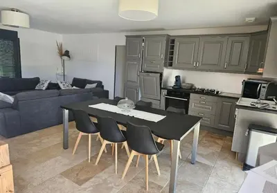 a kitchen and living room with a table and chairs at Les oliviers in Saint-Didier