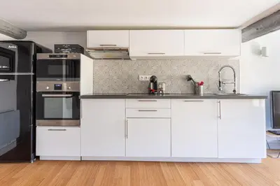 a kitchen with white cabinets and stainless steel appliances at Aixora - Centre historique - Tout à pied & parking in Aix-en-Provence