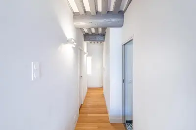 a hallway with white walls and wooden floors at Aixora - Centre historique - Tout à pied & parking in Aix-en-Provence