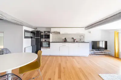 a kitchen with white cabinets and a table and chairs at Aixora - Centre historique - Tout à pied & parking in Aix-en-Provence