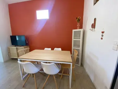 a dining room with a wooden table and white chairs at L appartement Lambescain in Lambesc