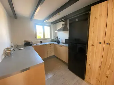 a kitchen with a black refrigerator and wooden cabinets at L appartement Lambescain in Lambesc