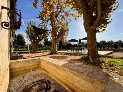 a water fountain in front of a building with trees at Mas d Anissa in Avignon