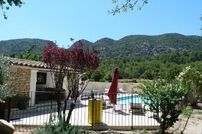 a house with a pool and mountains in the background at Villa Au Coeur Du Luberon in Maubec