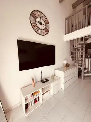 a living room with a tv and a clock on the wall at Duplex Cosy Aix proche CV terrasse clim parking in Aix-en-Provence