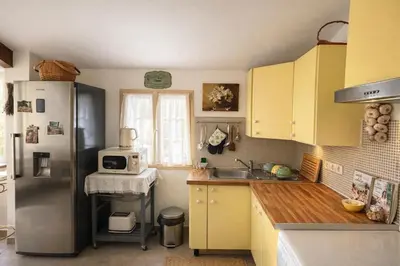 a kitchen with yellow cabinets and a stainless steel refrigerator at LaPetite Maison Abigail, Peaceful home in Avignon in Avignon