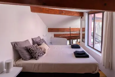 a large bed in a room with a large window at Duplex avec terrasse, au cœur d'Aix-en-Provence in Aix-en-Provence