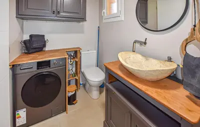 a bathroom with a sink and a washing machine at Maisonnette Avec Jacuzzi in Mazan