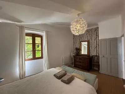 a bedroom with a bed and a window and a chandelier at Maison des Fontaines - Terrasse & vue sur vignoble, proche Aix-en-Provence 5 personnes - Domaine Viticole Château de Barbebelle, Rognes, Provence in Rognes