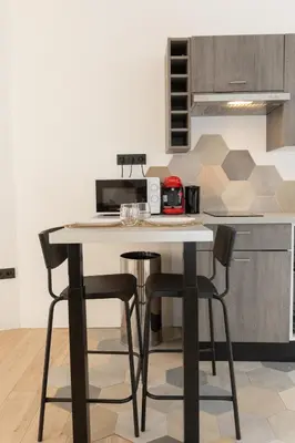 a kitchen with a table and two bar stools at Le Rimbaud - Studio moderne en hypercentre - WiFi in Carpentras