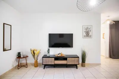 a living room with a tv on a white wall at T2 cosy avec jardin & parking gratuit - Quartier Beauregard in Aix-en-Provence
