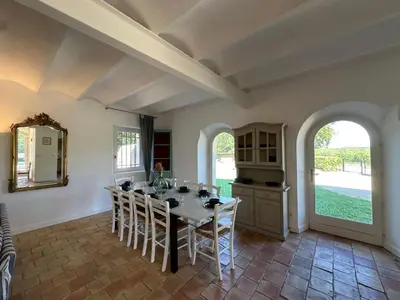 a dining room with a table and chairs and windows at Villa des Cyprès - Charmante maison provençale - Jardin et piscine privés au cœur d un Domaine Viticole Château de Barbebelle Rognes - 10 personnes - Proche d'Aix-en Provence in Rognes
