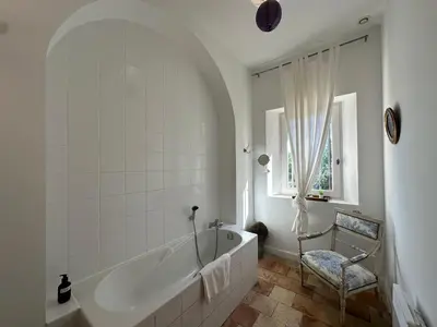a white bathroom with a tub and a chair at Villa du Puits - Séjour en Provence avec piscine privée & jardin au cœur d'un domaine viticole Château de Barbebelle - Rognes - Proche d'Aix-en-Provence -10 personnes in Rognes