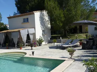 a swimming pool with chairs and an umbrella and a house at Les Anges in LʼIsle-sur-la-Sorgue