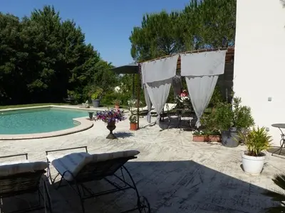 a patio with a pool and a table and chairs at Les Anges in LʼIsle-sur-la-Sorgue