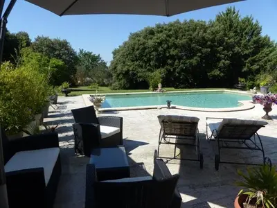 a patio with a table and chairs and a swimming pool at Les Anges in LʼIsle-sur-la-Sorgue