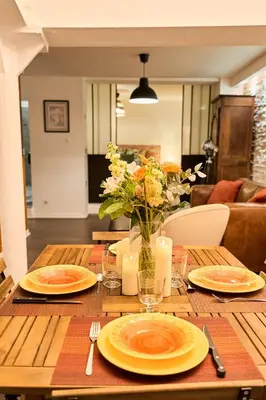 a wooden table with plates and a vase of flowers at Evasion au centre d Aix loft chic et cosy in Aix-en-Provence