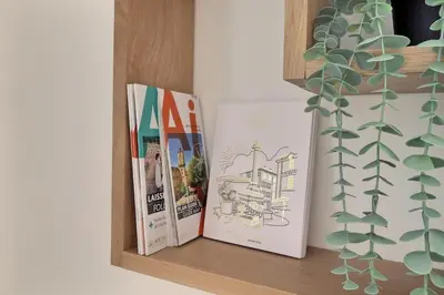 three books sitting on a shelf next to a plant at La Parenthèse Aixoise - 3 stars - Parking - Clim in Aix-en-Provence