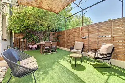 a patio with chairs and a table and a fence at La Cour de Pétrarque in Fontaine-de-Vaucluse