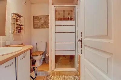 a bathroom with a toilet and a sink and a door at La Cour de Pétrarque in Fontaine-de-Vaucluse