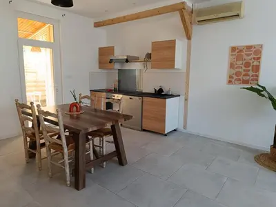 a kitchen with a wooden table and chairs in a room at La Villa des Trois in Cavaillon