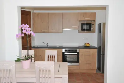 a kitchen with wooden cabinets and a table with chairs at Domaine la Garenne in Saint-Marc-Jaumegarde