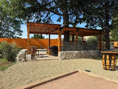 a wooden pavilion with a picnic table and a bench at Villa Soleil Piscine Jacuzzi Pétanque Espace bbq billard et salons extérieurs in Aix-en-Provence