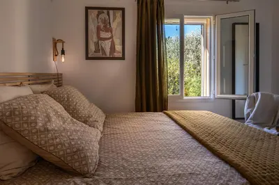 a bedroom with a large bed with a window at La Colline - Pause Provençale in LʼIsle-sur-la-Sorgue