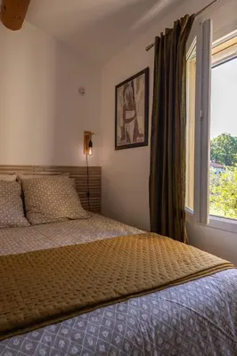 a bedroom with a bed and a large window at La Colline - Pause Provençale in LʼIsle-sur-la-Sorgue
