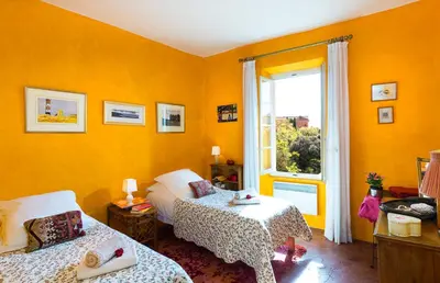 a yellow room with two beds and a window at Maison Vignes in Roussillon