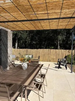 a patio with a table and chairs under a wooden umbrella at Villa Mimosa in Venasque