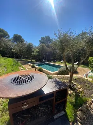 a fire pit in a yard next to a swimming pool at Le bois des chênes in Peypin-dʼAigues