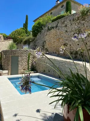 a swimming pool in front of a brick wall at Bastidon, Petite bastide pour 2 avec bassin et jardin privé in Crillon-le-Brave