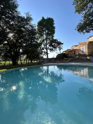 a pool of blue water with trees in the background at Magnifique Mas provencal au coeur des vignes in Mazan