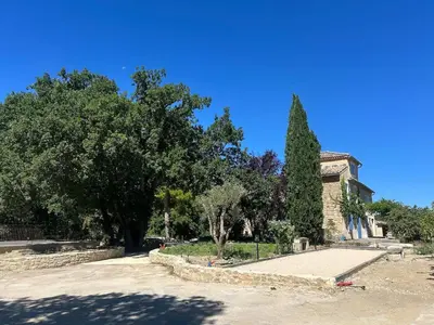 a building with a tree in a park at Magnifique Mas provencal au coeur des vignes in Mazan