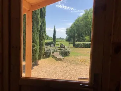 a window with a view of a park with a bench at chalet le domaine des cigales in Cavaillon