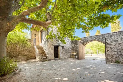 an external entrance to a stone building with a tree at Mas de Thésée Piscine & 12 ha privés in Reillanne