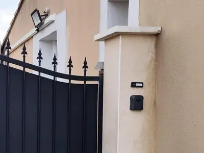 a black gate on the side of a house at Petite maison de charme in LʼIsle-sur-la-Sorgue