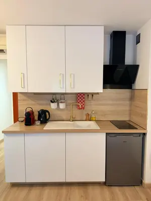 a kitchen with white cabinets and a sink at Le Clos d'AIX studio 1 in Aix-en-Provence