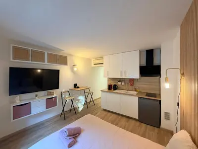 a kitchen with white cabinets and a table in a room at Le Clos d'AIX studio 1 in Aix-en-Provence