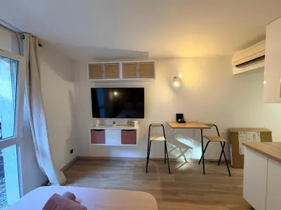 a living room with a table and a tv on the wall at Le Clos d'AIX studio 1 in Aix-en-Provence