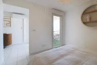 a white bedroom with a bed and a large window at Le Nid du Pradon in Cavaillon