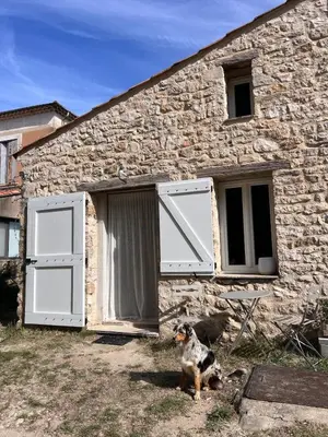 a dog sitting in front of a stone building at Studio cosy à la campagne in Montjustin