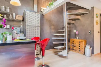 a kitchen with a counter and red chairs in a room at Urban loft with terrace downtown in Aix-en-Provence