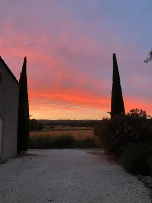 a sunset over a field with trees and a building at Mas Provençal avec piscine à Gordes in Gordes